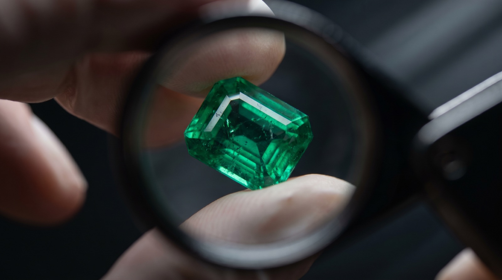 A jeweller inspecting a green emerald through a loupe